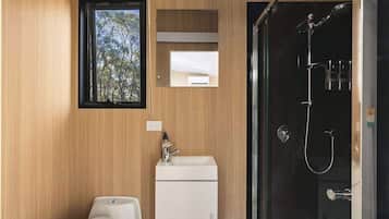 A modern bathroom with a wooden wall, a window, a sink, and a shower.