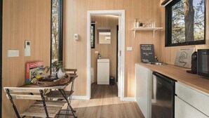 Eine kleine Küche mit Holzarbeitsplatte, Spüle und Kühlschrank. Ein Monopoly-Spiel ist links zu sehen, und ein Schild verkündet: 'Welcome to Black Forest Hideaway'.