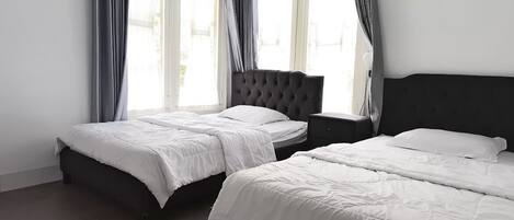 A hotel room with two beds, a dark headboard, and a nightstand.