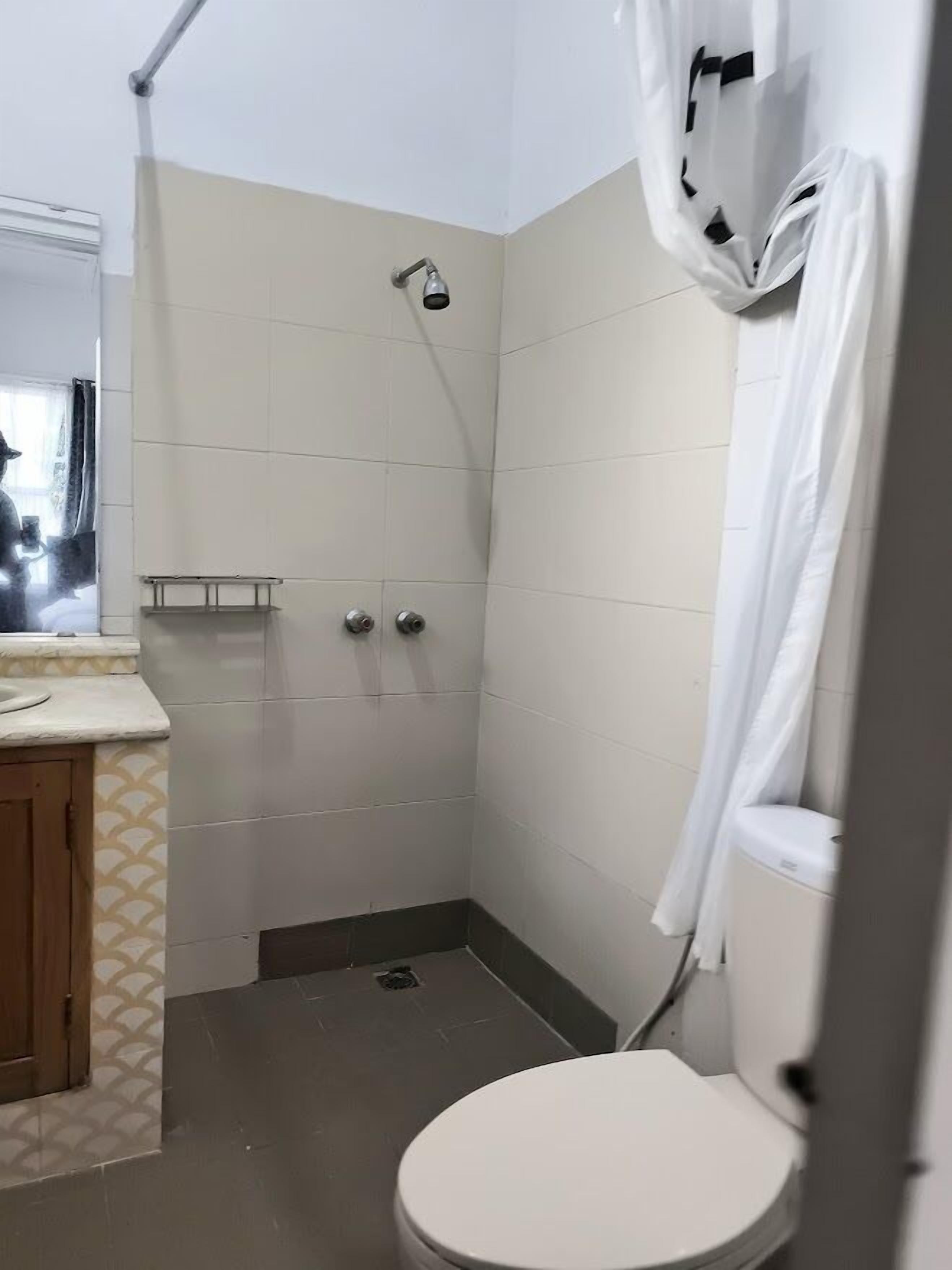 Ein kleines Badezimmer mit Fliesen, einer Toilette, einer Dusche und einem Waschbecken.