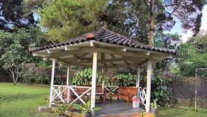 A gazebo with a tiled roof, wooden benches, and potted plants. - Villa Narendra Yogyakarta (Pakem)
