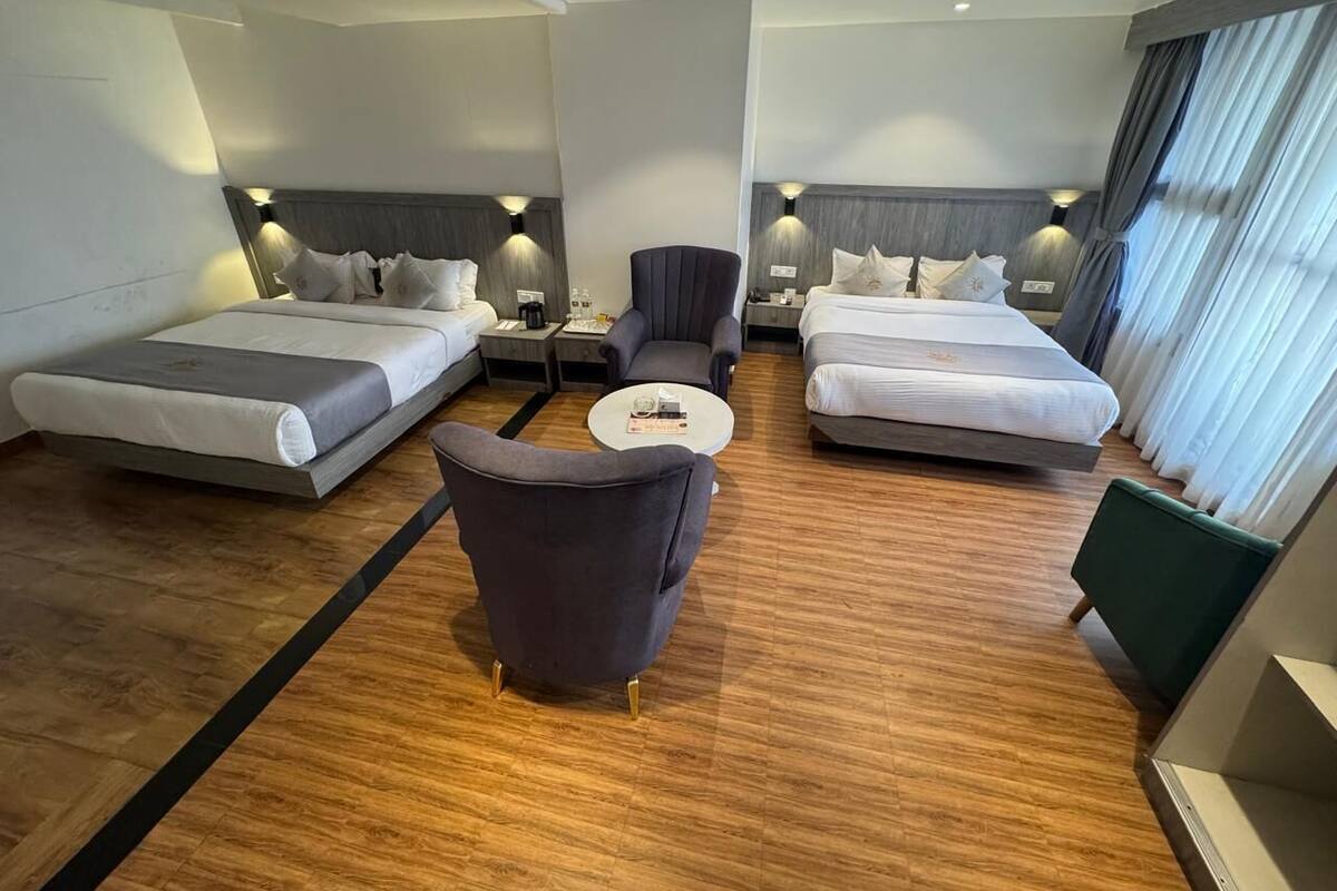 A hotel room with two beds, a sofa, a coffee table, and a chair.