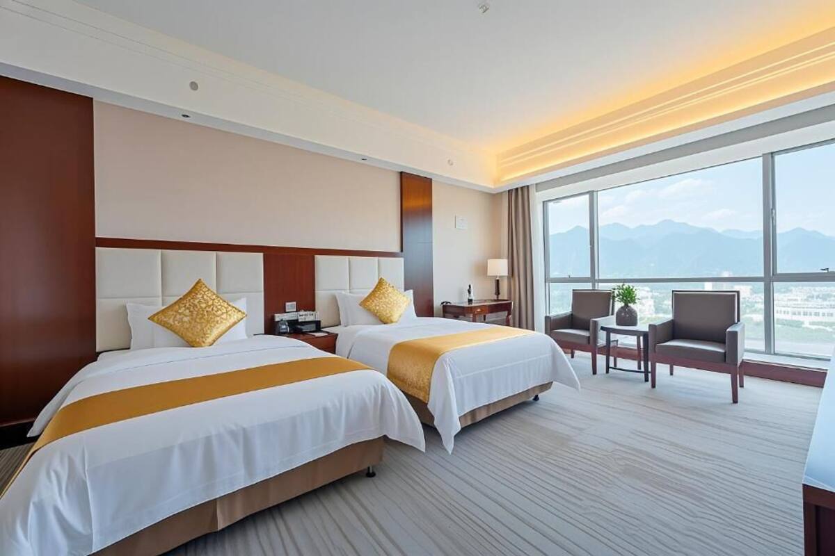 Habitación de hotel con dos camas, un escritorio y vistas a las montañas.