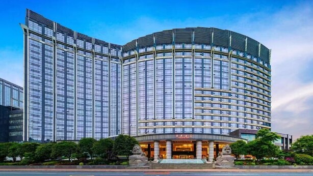 Un hotel moderno con fachada curva, varios pisos y una entrada destacada con una estatua.