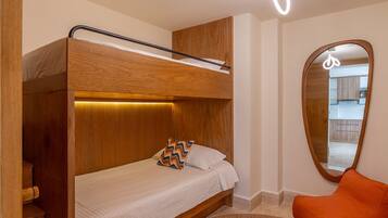 Una cama individual con cabecera de madera, un tapete redondo tejido y una luminaria de techo brillante.
