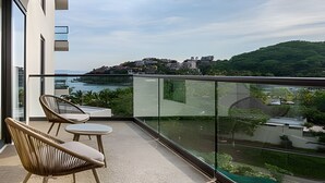 A balcony with two chairs and a small table, overlooking a coastal town and a hill. - Zantamar 501 C (La Cruz de Huanacaxtle)
