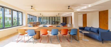 Una habitación amplia con una mesa larga y sillas, ventanas grandes y un sofá moderno.