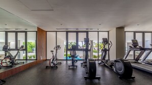 A gym with various exercise equipment, large windows, and a view of greenery outside. - Zantamar 501 C (La Cruz de Huanacaxtle)
