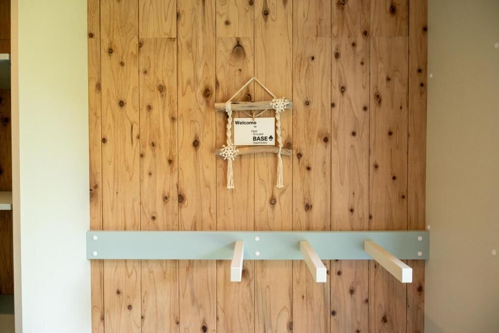 A wooden wall with a hanging sign that reads "Welcome to BASE."