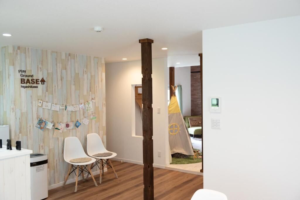 Un espace d’accueil doté d’un plancher en bois, de chaises blanches, d’un comptoir de réception et d’une enseigne fixée au mur.