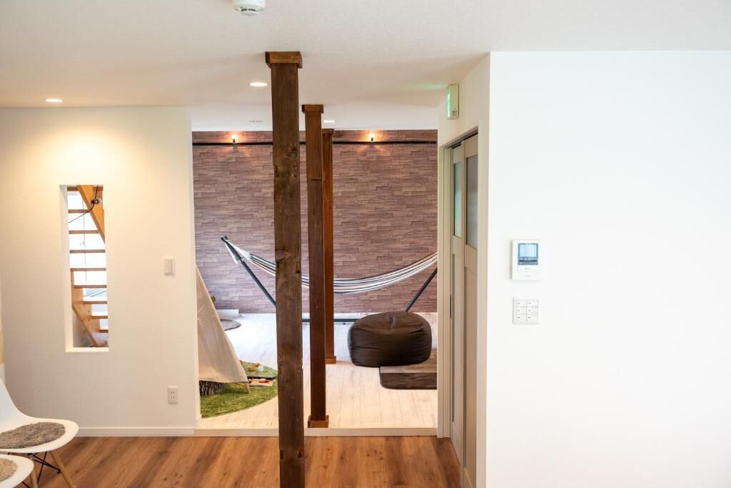 A modern interior with a hammock, wooden columns, and a view of a garden.
