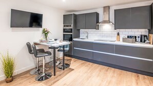 A modern kitchen with dark cabinets, a built-in oven, and a large island with a sink. - Fishertown Apartment by Interhome (Nairn)