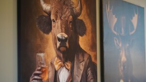 A bull head with horns and a bow tie holding a glass.
