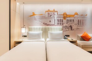 Une chambre d’hôtel avec deux lits, une table de chevet avec une lampe, un téléphone et une fresque murale représentant un bâtiment.