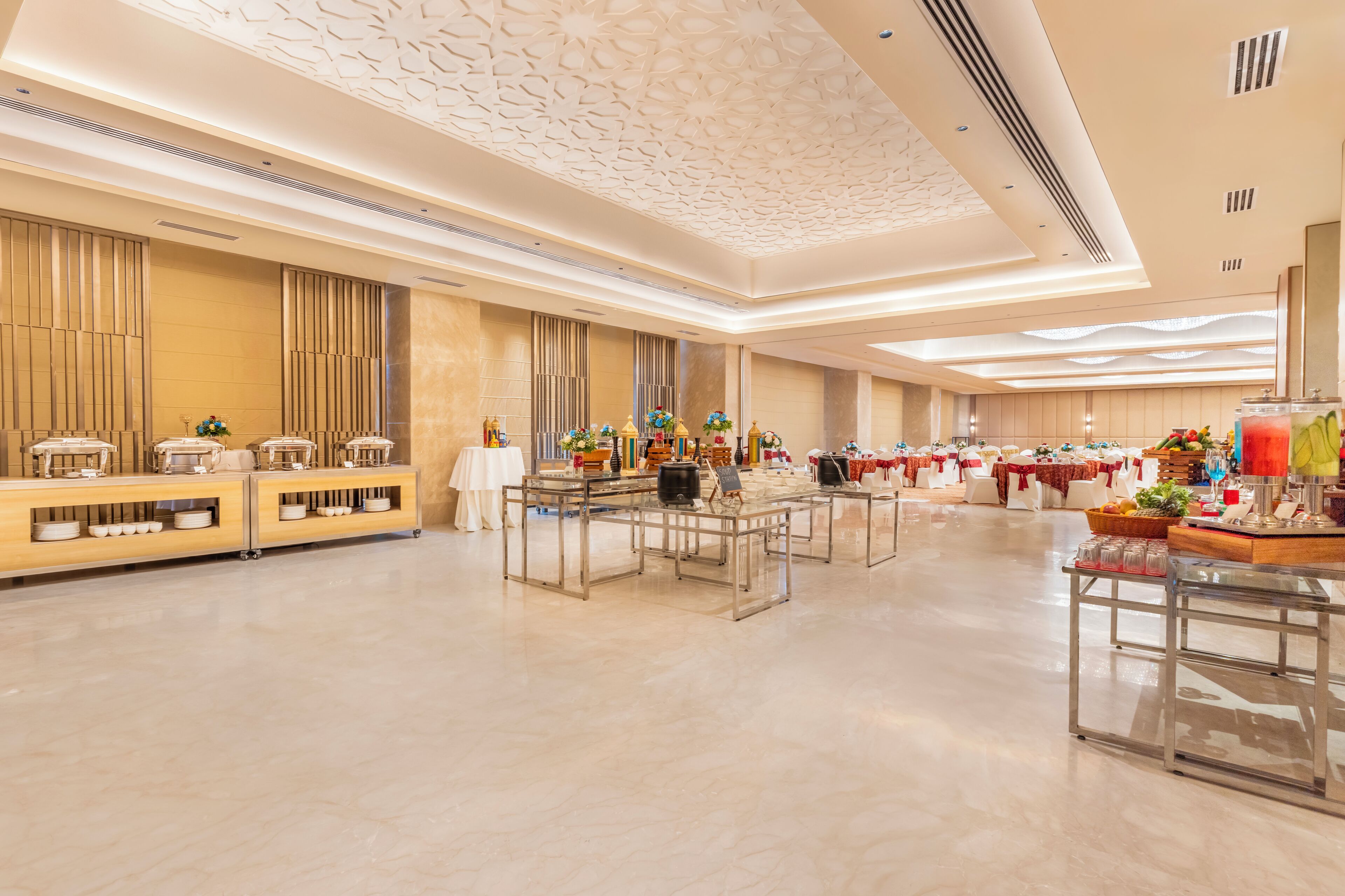 A spacious banquet hall with a polished floor, long tables set for dining, and a decorative ceiling.