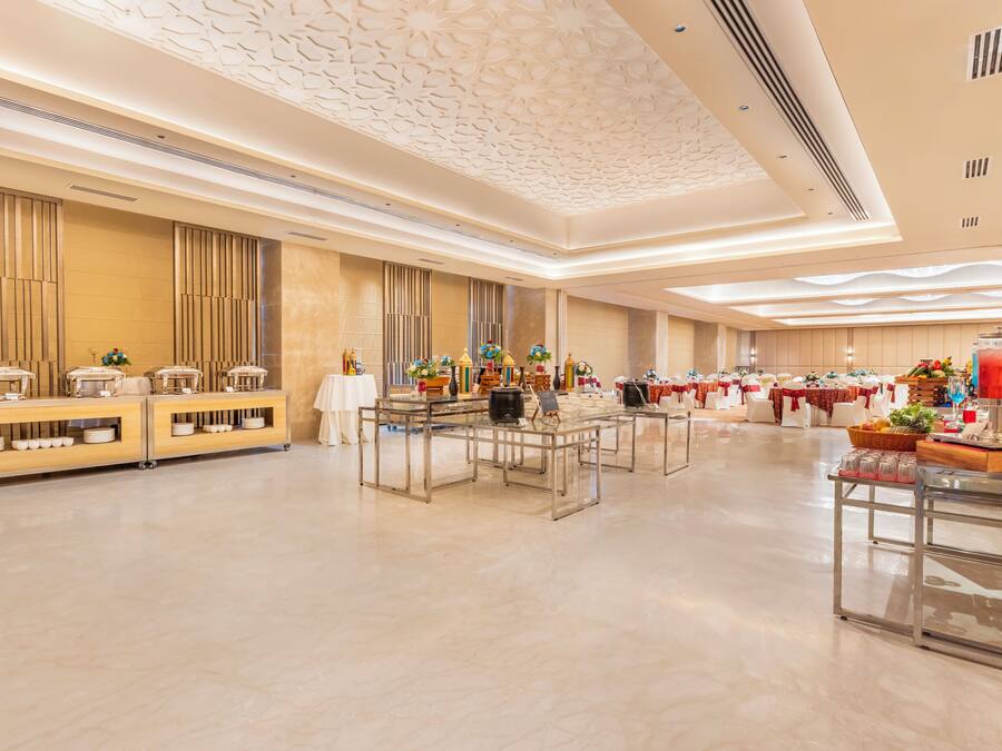 A spacious banquet hall with a polished floor, long tables set for dining, and a decorative ceiling.