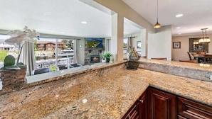 A kitchen with granite countertops, a stone fireplace, and a view of the outside.