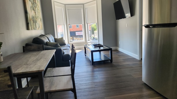 Et moderne køkken med spiseplads, sofa og tv ophængt på væggen.
