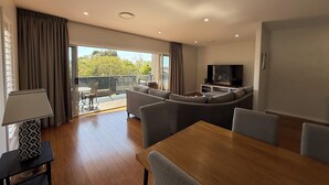Ein modernes Wohnzimmer mit einem Holzesstisch, grauen Sofas und einem Flachbildfernseher.