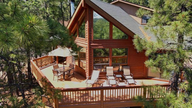 A wooden cabin with a deck, outdoor seating, and large windows. - Spacious Family Mountain Cabin ~Fireplace ~2 Decks ~Near Lake (Munds Park)