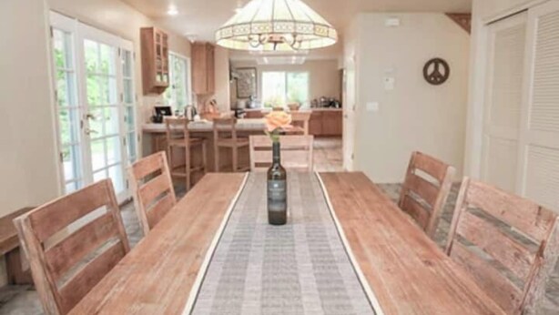 A dining area with a long wooden table, chairs, and a chandelier.