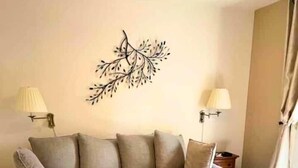A living room with a grey sofa, a round coffee table, and two wall-mounted lamps.