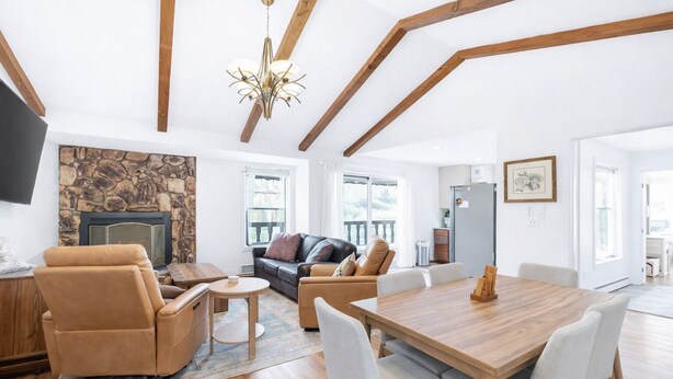 A spacious living area with a stone fireplace, a wooden dining table, and a comfortable seating arrangement.