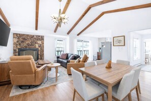 A spacious living area with a stone fireplace, a wooden dining table, and a comfortable seating arrangement.