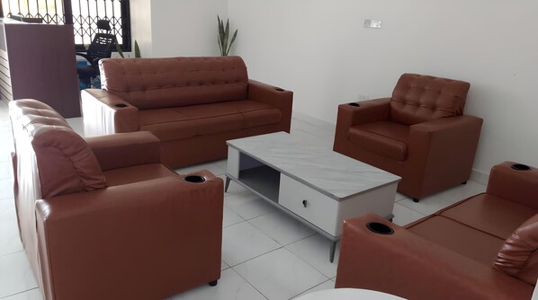 A modern living room with a sofa set, a coffee table, and a chair. - Sleepeaze Hotel (Afienya)