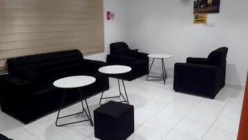 A room with a black sofa set, two round tables, and a black ottoman.