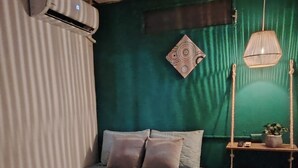 Une chambre à coucher avec un lit, des oreillers, une table de chevet avec une lampe et un mur vert.
