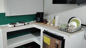 Une petite cuisine équipée d’une cuisinière, d’une machine à café et d’un réfrigérateur.