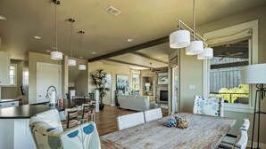 A spacious living area with a wooden dining table, comfortable seating, and pendant lighting.