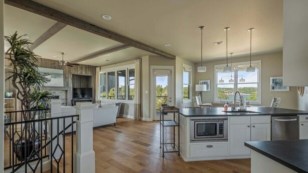 A spacious kitchen with a central island, wooden flooring, and large windows.