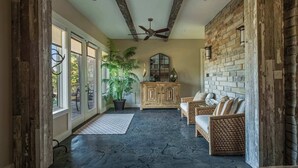A room with a ceiling fan, a large potted plant, a wooden cabinet, and wicker furniture.