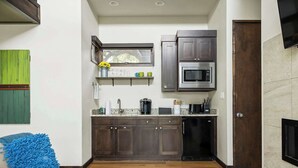 A compact kitchen with dark wood cabinets, a built-in microwave, and a dishwasher. - Charming Lake Getaway with Loft / Pickleball / BBQ (Lake Travis)