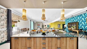 A modern kitchen with a central island, pendant lighting, and a vibrant wall mural.