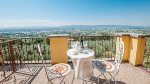 Een balkon met een tafel voor twee personen, met uitzicht op een prachtig landschap.