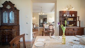 Een eethoek met een houten kast, een gedekte eettafel voor twee personen en een vaas met bloemen.