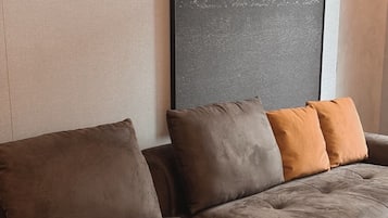 A sectional sofa with multiple cushions in a neutral color palette, positioned against a textured wall.
