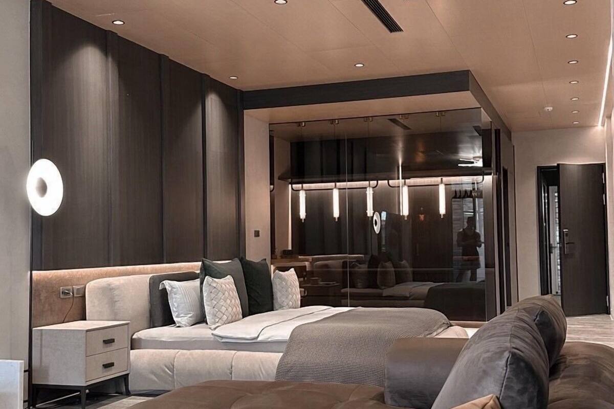 A modern living room with a large sectional sofa, a glass partition, and recessed lighting.