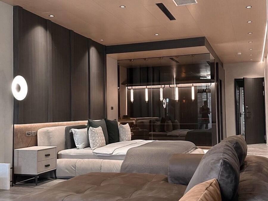 A modern living room with a large sectional sofa, a glass partition, and recessed lighting.