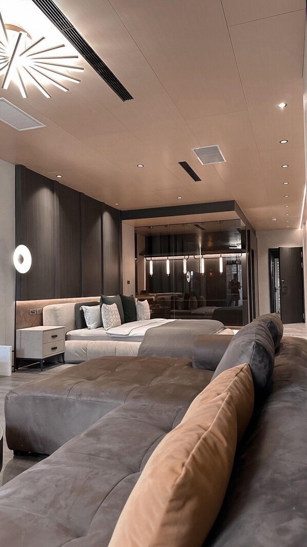 A modern living room with a large sectional sofa, a glass partition, and recessed lighting. - Here Hotel - Pingtung A (Pingtung)