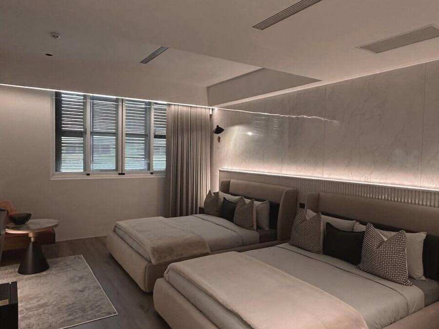 Ein modernes Schlafzimmer mit zwei Betten, einem großen Fenster und einer eingebauten Kopfteil.