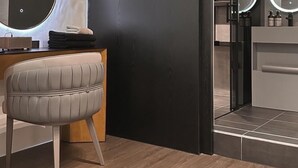 A modern bathroom with a dark wall, a round mirror, and a vanity with a lighted mirror. - Here Hotel - Pingtung A (Pingtung)