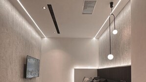 A modern bedroom with a bed, a round rug, a TV, and a desk with a lamp. - Here Hotel - Pingtung A (Pingtung)