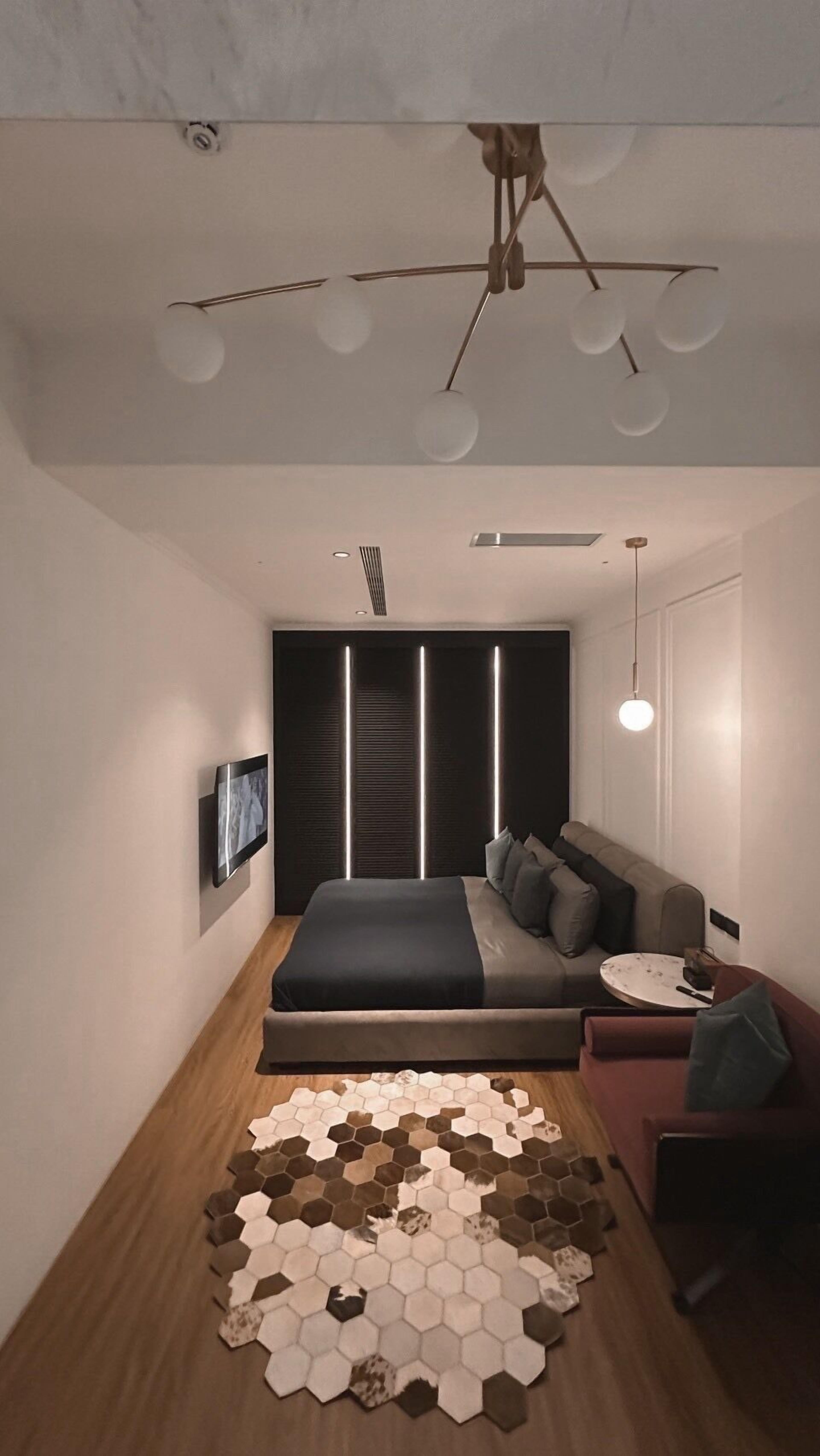 Une chambre à coucher moderne avec un lit, un canapé, une table basse ronde et un tapis hexagonal.