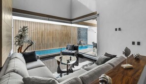 A modern living room with a pool, a sofa, a coffee table, and a wooden accent wall. - Villa 83: 3BR, 2 Private Pools & Beach Club Access (Cruz de Huanacaxtle)