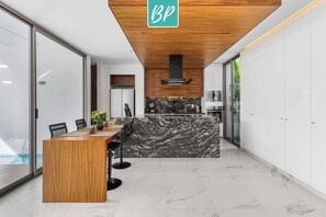 A modern kitchen with a marble countertop, wooden ceiling, and a sign with 'BP' on it. - Villa 83: 3BR, 2 Private Pools & Beach Club Access (Cruz de Huanacaxtle)
