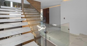 Una escalera moderna con barandillas de vidrio y peldaños de mármol.